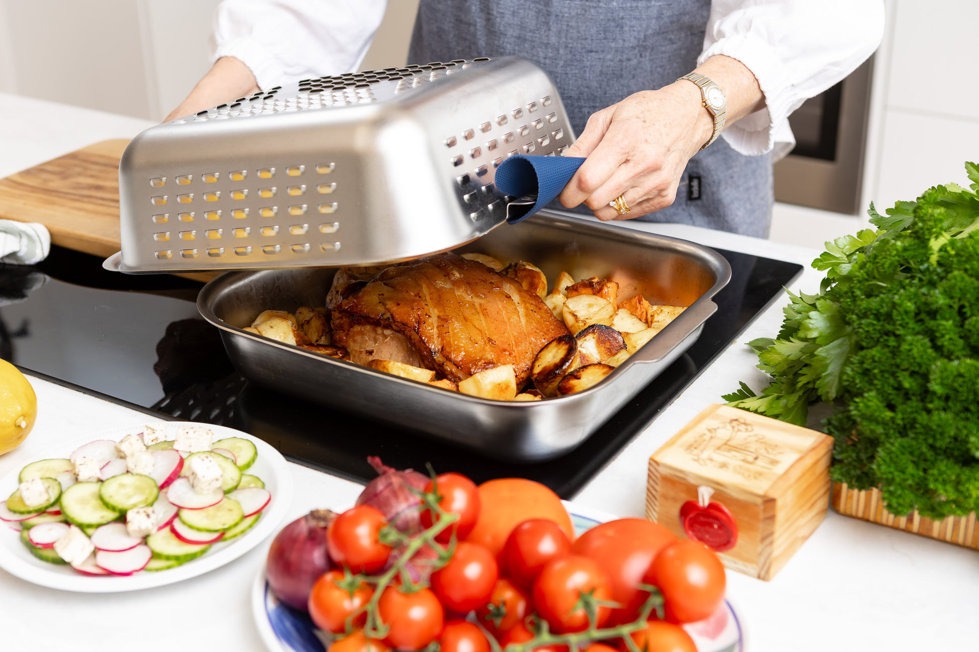 Stainless steel spatter guard cover being lifted off perfectly cooked pork roast. Roast more. Clean Less. With the Hagane Ultimate Roaster.